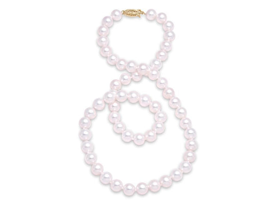 A long Mastoloni Pearls freshwater pearl necklace, named "Frshwater Pearl Pearl Necklace / 14 Kt Y /8.5MM," is laid out on a white surface. The necklace, with its 14 Kt gold clasp, is arranged in a loose and elegant serpentine shape, showcasing the shiny, round pearls.