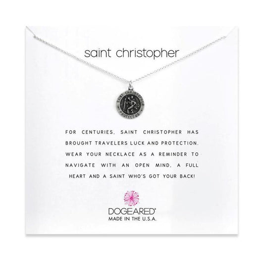 A Dogeared Saint Christopher / SS necklace, 18 inches long, displayed on a white card. The card reads, "For centuries, Saint Christopher has brought travelers luck and protection. Wear your necklace as a reminder to navigate with an open mind, a full heart, and a saint who's got your back!