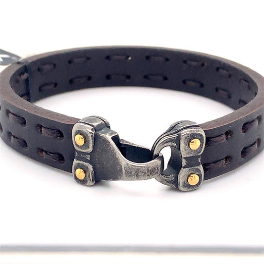 The Men's Brown Leather Bracelet by INOX measures 8 1/4 inches in length and features an industrial-style silver clasp with an antiqued gun metal steel closure. It is adorned with four small brass rivets, and the leather band showcases a double-row of rectangular cutout patterns for a rugged yet stylish appearance.