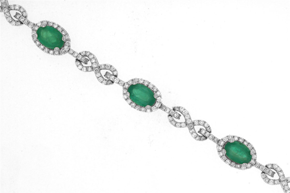 Introducing the Emerald and Diamond Bracelet, Style # WH1074E by Royal Jewelry. This exquisite silver bracelet features four oval emerald gemstones, each elegantly surrounded by small white stones. Intricately looped links encrusted with additional white stones enhance its elegant design, reminiscent of a classic diamond bracelet. Set against a plain white background, this piece weighs 2 CT and captures timeless sophistication.