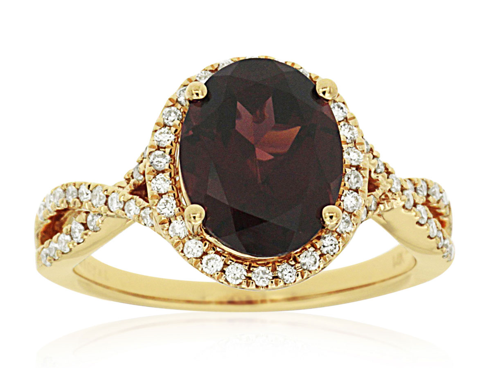 The Royal Jewelry 14k YG Garnet and Diamond ring, size 7, showcases a large oval garnet as its centerpiece, encircled by a halo of dazzling diamonds. The band is adorned with additional diamonds in an elegant twist design.