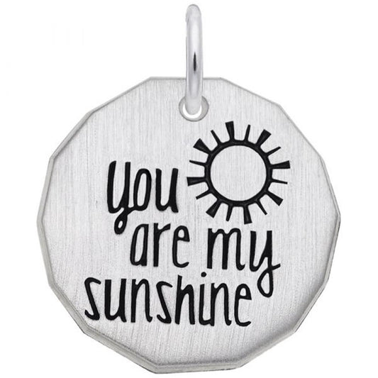 The "You Are My Sunshine Charm" by Rembrandt Charms is a sterling silver, octagon-shaped pendant featuring a small sun icon and the inscription "You Are My Sunshine" in black, stylized lettering. The pendant has a small metal loop at the top for easy attachment to a chain.