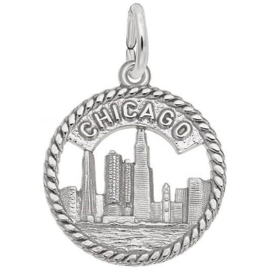 The Rembrandt Charms Chicago Skyline Charm in sterling silver features a detailed depiction of the Chicago skyline, with the word "CHICAGO" prominently displayed at the top. The charm is encircled by a rope-like border that frames the city's buildings and a body of water at the bottom, making it an exquisite accessory for any lover of the Windy City.