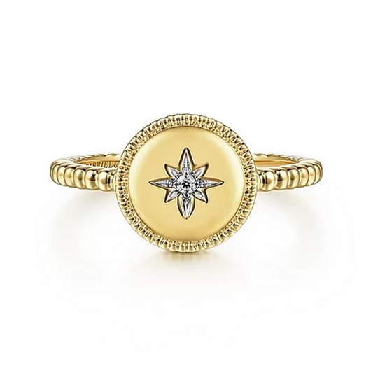 The 14K Yellow Gold Round Diamond Star Bujukan Ring from Gabriel & Co features a beaded band with a round, flat top adorned with a starburst design. At the center of the starburst is a small, sparkling round diamond set in 14K Yellow Gold. The edges of the round top are intricately detailed, adding elegance to this exquisite piece from the Bujukan Collection.