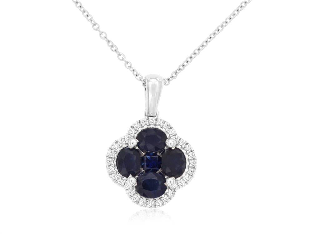 The Royal Jewelry Sapphire and Diamond Clover Pendant showcases a design where four sapphire gemstones are elegantly arranged in a floral motif, surrounded by a border of small, sparkling diamonds, hanging from what appears to be a silver chain.