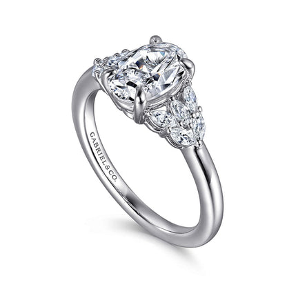 A stunning 14K white gold engagement ring by Gabriel & Co showcases a large oval diamond as its centerpiece, accented by two smaller natural diamonds on each side. The silver band is elegantly engraved with "Gabriel & Co" for a personalized touch of elegance.