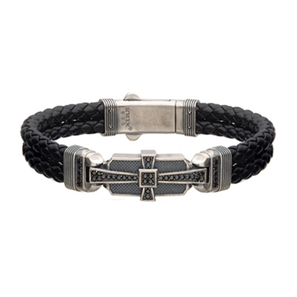 The Men's Black Leather with 925 Silver and 40 pcs Black CZ Deco Bracelet by INOX showcases a black braided leather band complemented by an intricate silver clasp adorned with cross-like details. The metal parts feature small black cubic zirconia stones, adding a textured and elegant touch to the overall design.