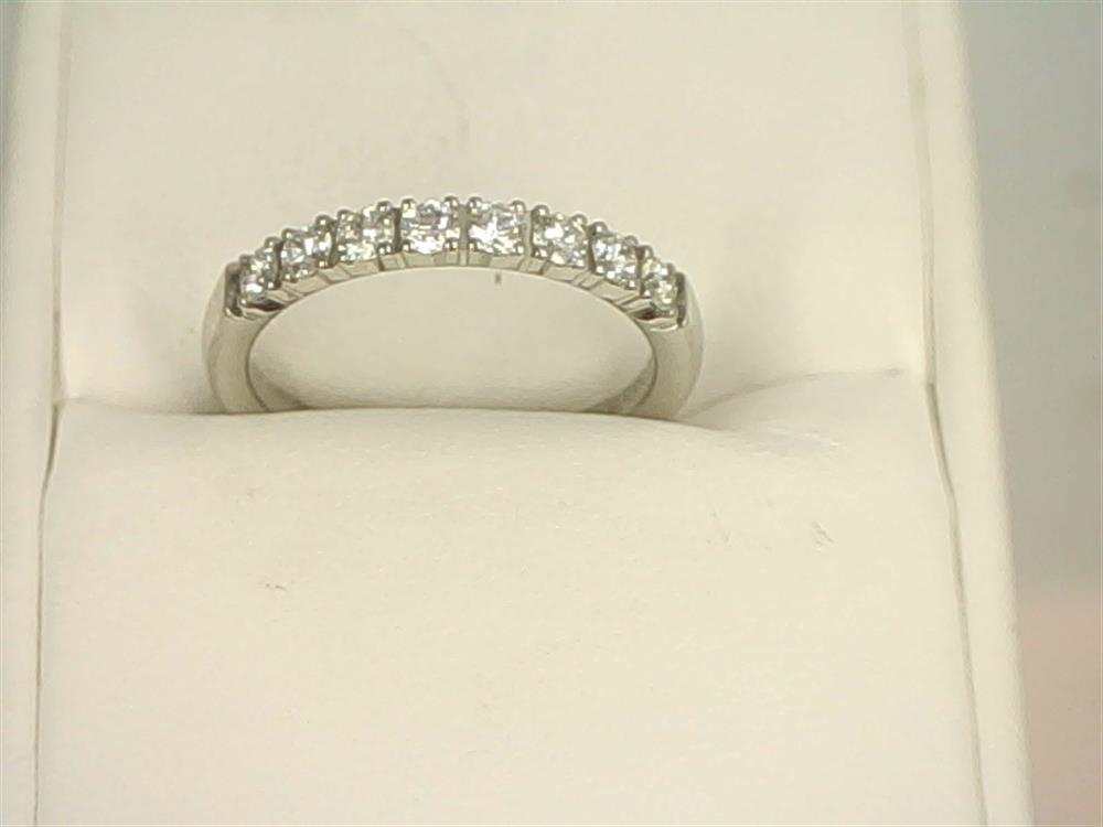 A stunning 14K White Gold .4800ctw Round Cut Diamond Anniversary Band by Benchmark Rings, adorned with multiple small lab-grown diamonds along the top half, gracefully displayed in an open white jewelry box.