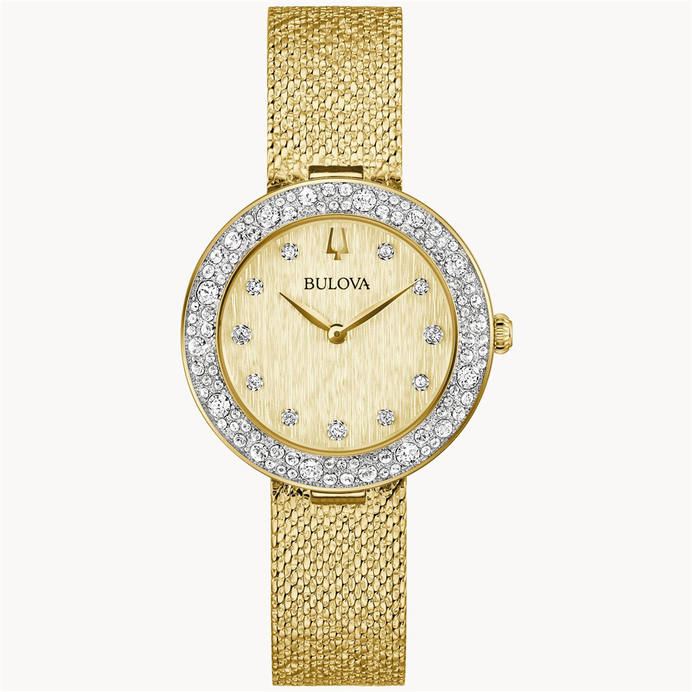 A Bulova Watch Company wristwatch in gold features a textured mesh band. Its round champagne face is adorned with diamond hour markers and surrounded by a 103 Austrian crystal-studded bezel. Simple watch hands are complemented by a crown located on the right side.