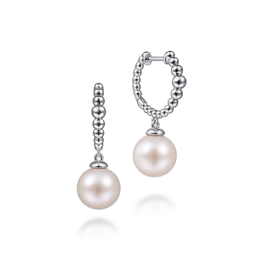 A pair of elegant Gabriel & Co 925 Sterling Silver Bujukan Pearls Drop Huggie Earrings featuring a round white Bujukan pearl dangling from a 925 Sterling Silver hoop made of small interconnected silver beads. The drop huggie earrings boast a polished, shiny finish and are displayed on a plain white background.