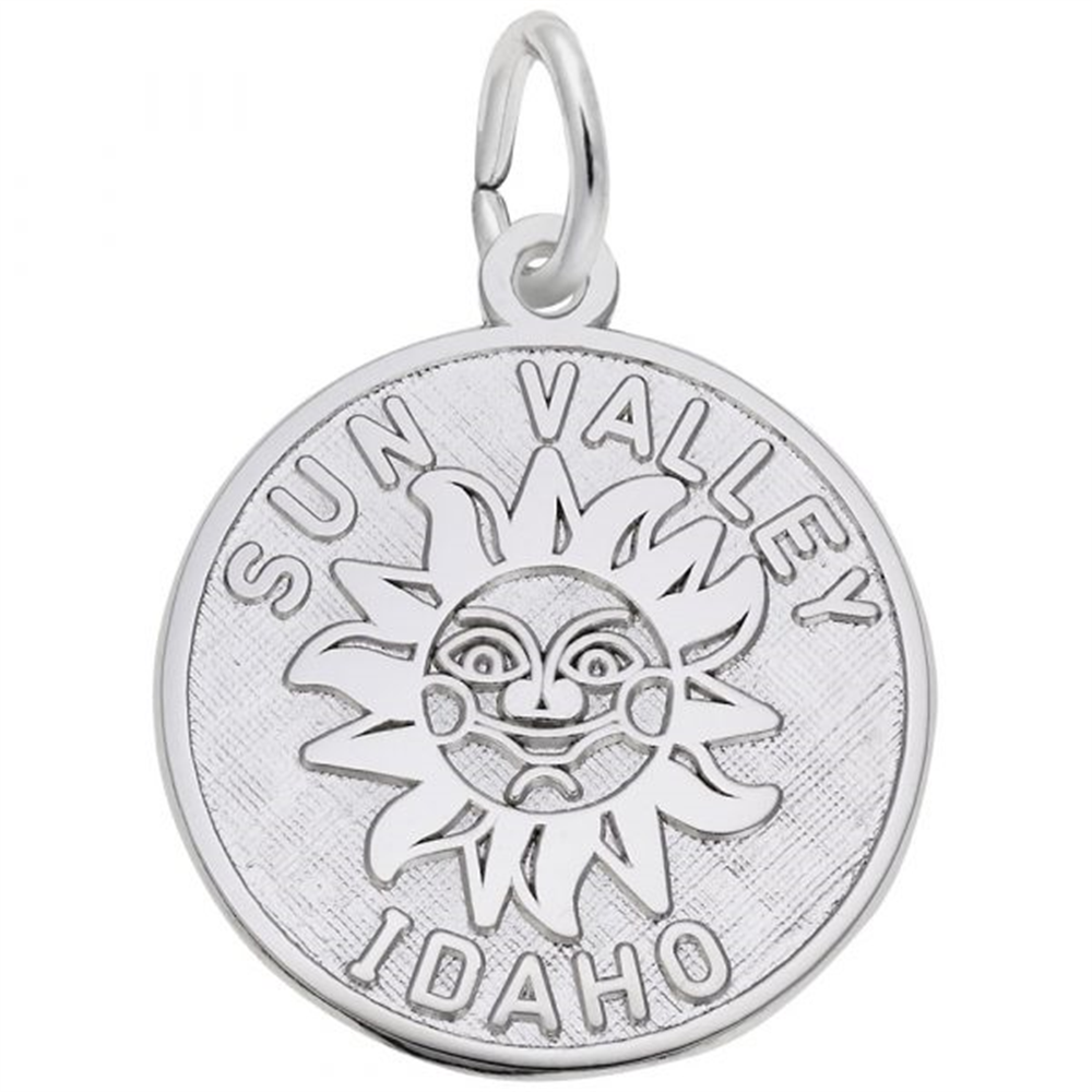 The Sun Valley Idaho Disc Charm by Rembrandt Charms is a sterling silver pendant featuring an engraved smiling sun with detailed facial features. The words "SUN VALLEY" are inscribed above the sun, and "IDAHO" below it. This charm includes a loop at the top for attaching to a chain or keyring.