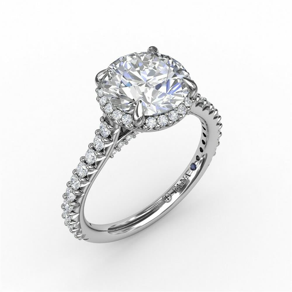 The 14K White Gold Contemporary Round Diamond Halo Engagement Ring With Geometric Details by FANA showcases a stunning large round diamond at its center, encircled by smaller conflict-free diamonds. The band is elegantly decorated with a single line of smaller diamonds, enhancing the ring's overall sparkle and elegance.