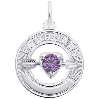 The February Love Birthstone Charm by Rembrandt Charms features a sterling silver pendant with a circular design. The word "February" is elegantly engraved on the top half, while a purple heart-shaped gemstone, symbolizing the February Birthstone, is set in the center and pierced horizontally by a delicate silver arrow.