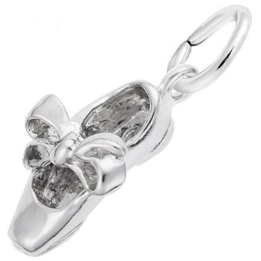 A close-up image of a sterling silver Tap Shoe Charm by Rembrandt Charms. The charm features a detailed bow on top of the shoe and has a small loop attached to the heel for use with a necklace or charm bracelet. The overall design is sleek and polished, emphasizing the delicate details.