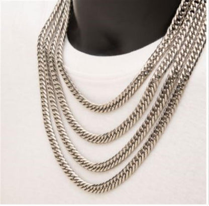 A close-up image of a person wearing the 8mm Steel Dome Curb Chain by INOX, layered beautifully around their neck. The chains, measuring 22 inches each, feature a robust design with thick, interlocking links. The person’s white garment provides a striking contrast to the metallic sheen of these men's stainless steel necklaces from INOX.