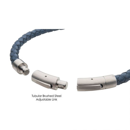 A close-up of the 6mm Blue Genuine Leather Bracelet by INOX features a woven blue band and an adjustable brushed tubular press clasp. The bracelet is open at the steel clasp, revealing its connecting mechanism. There is text labeling the link as "Brushed Tubular Press Clasp.