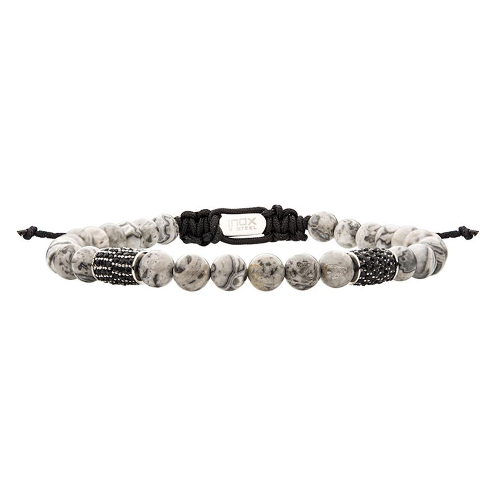 The "Stainless Steel Beads with Black CZ & Grey Jasper Stone Bead Adjustable Bracelet" by INOX features a stylish white and gray marbled bead design. It also includes several Black CZ rhinestone bead accents prominently in the middle, complemented by Grey Jasper Stone beads throughout. The bracelet comes with a black woven adjustable cord adorned with a small metallic rectangular tag engraved with the brand name "INOX.