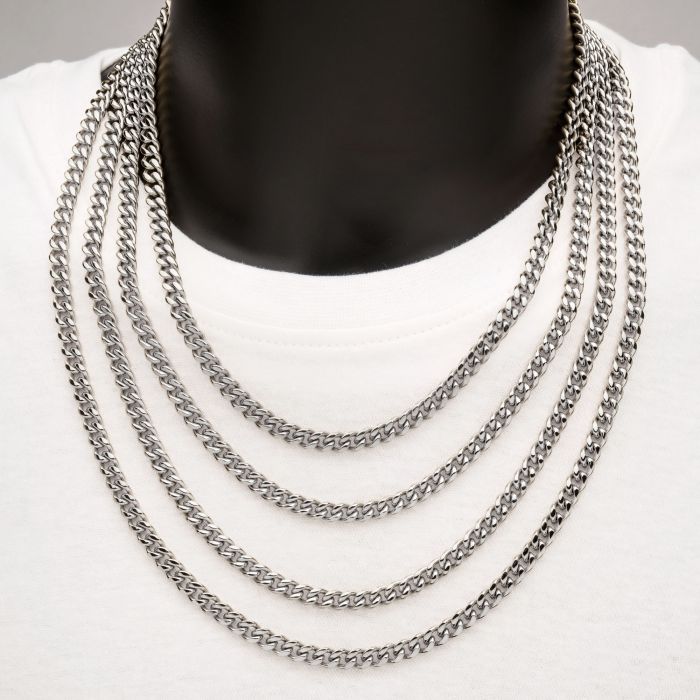 A person wearing a white shirt and the 6mm Steel Miami Cuban Chain by INOX, featuring closely linked chains lying neatly against the shirt, creating a cascading effect.