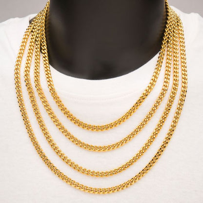 A close-up image of a person wearing a white shirt and showcasing several layers of INOX 8mm 18K Gold Plated Miami Cuban Chain necklaces, each measuring 20 inches. The necklaces are neatly arranged in a staggered fashion around the neck, creating a luxurious, elegant appearance against the contrasting background.