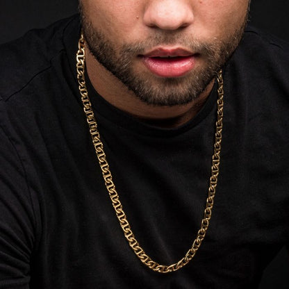 A close-up of a person wearing a black shirt and an 8mm 18K Gold Plated Mariner Link Chain from INOX, measuring 24 inches. The focus is on the lower half of their face, highlighting their lips, beard, and the intricate design of the men's stainless steel necklace set against a dark background.