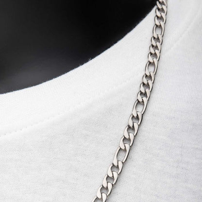 Close-up of the 6mm Steel Figaro Chain by INOX draped over the neckline of a plain white shirt. The image highlights the interlinked design against the fabric texture, with a dark background providing striking contrast. This 22" Men's Stainless Steel Necklace adds an elegant touch to any outfit.