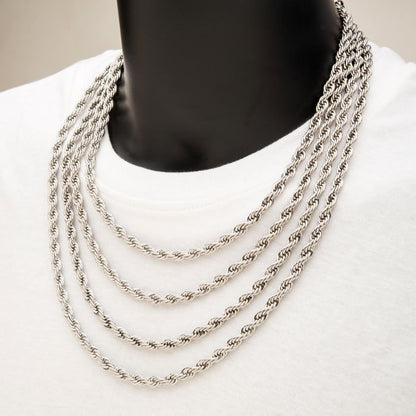 A person wearing a white shirt is adorned with four 6mm Steel Rope Chains from INOX, each varying in length and layered one above the other. These men's necklaces rest neatly on the chest, with their intricate twists capturing the light and adding a subtle shine to the overall appearance.