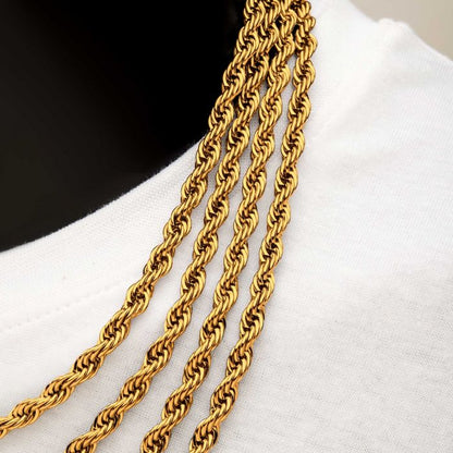 A close-up image of four twisted rope-style gold chains, including the 6mm 18K Gold Plated Rope Chain from INOX, draped over the shoulder of a mannequin dressed in a white shirt. The intricate design of the chains showcases their shiny and detailed craftsmanship.