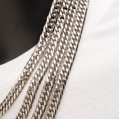 Close-up of several thick 8mm Steel Dome Curb Chains by INOX displayed on a white fabric background. The curb chains are tightly interlocking, creating a sleek and shiny surface. This arrangement of 22-inch men's necklaces showcases their intricate design and craftsmanship perfectly.