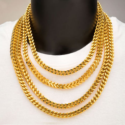 Four gold-plated Franco chains by INOX are displayed on a person wearing a white shirt. Each 4mm 18K gold-plated chain, measuring 22 inches long, has thick, closely interlocking links and gradually increases in length from top to bottom, creating a cascading effect.