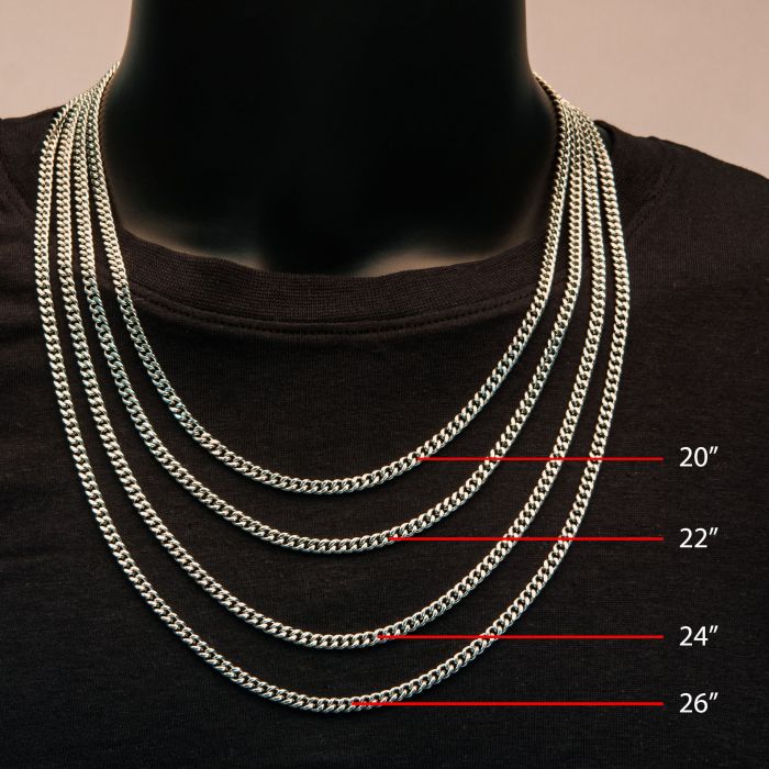 A person wearing multiple silver chains of different lengths around their neck on a black t-shirt. The 24" chain stands out as the 8mm Diamond Cut Curb Chain Necklace by INOX, labeled alongside the others from top to bottom as 20 inches, 22 inches, 24 inches, and 26 inches.