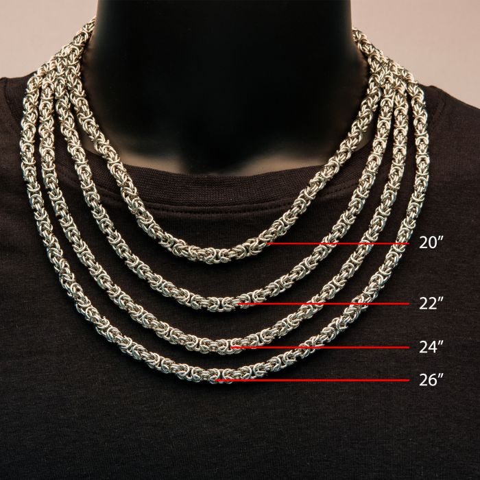 A black mannequin adorned with four men's INOX 6mm Steel King Byzantine chains of varying lengths—20, 22, 24, and 26 inches. Each exquisite chain is layered over the other, creating a striking display against the neutral background.