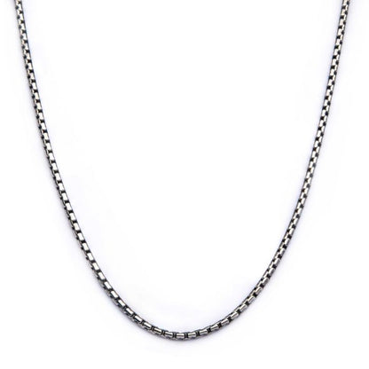 A close-up image of the INOX 3mm Oxidized Steel Boston Link Chain, a men's necklace with a silver stainless steel chain showcased against a white background. The 24-inch chain is simple and elegant, forming a U-shape as it lies flat to display the interlocking square-shaped links.