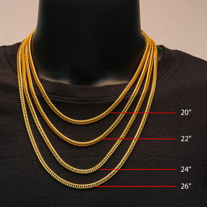 A mannequin adorned in a black shirt exhibits four INOX 18K gold plated chains of different lengths, specifically labeled from top to bottom as 20 inches, 22 inches, 24 inches, and 26 inches. Among these elegant men's accessories is the stylish Foxtail Chain Necklace by INOX, measuring at 20 inches.