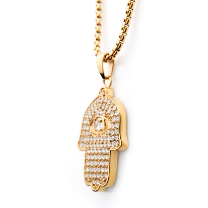 The 18K Gold Plated CZ Hamsa Pendant by INOX features a hand-shaped Hamsa pendant encrusted with small AAA CZ diamonds and an embedded, larger diamond at its center symbolizing an eye. This exquisite piece hangs from a 22" gold plated box chain.