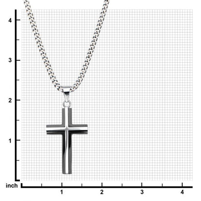 A sleek, Stainless Steel Black Plated & Steel 3D Cross Pendant with chain by INOX is displayed on a grid background. The grid has measurements in inches along both the x and y axes, with each square representing 0.5 inches. The men's INOX cross pendant measures approximately 1.5 inches tall.